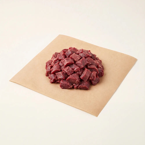 Diced raw venison on a piece of brown paper with a white background