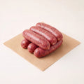 Six raw venison sausages on a piece of brown paper with a white background