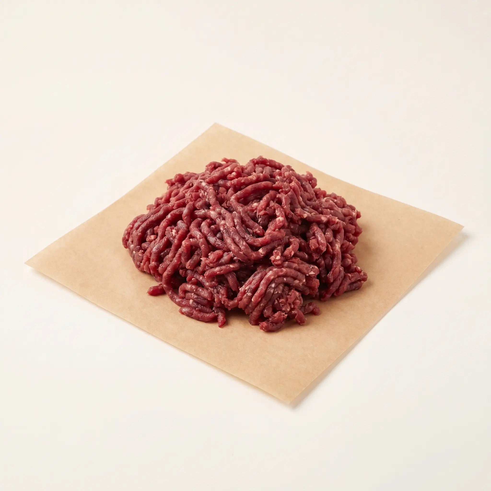 Raw ground venison mince on brown butcher paper against a white background.