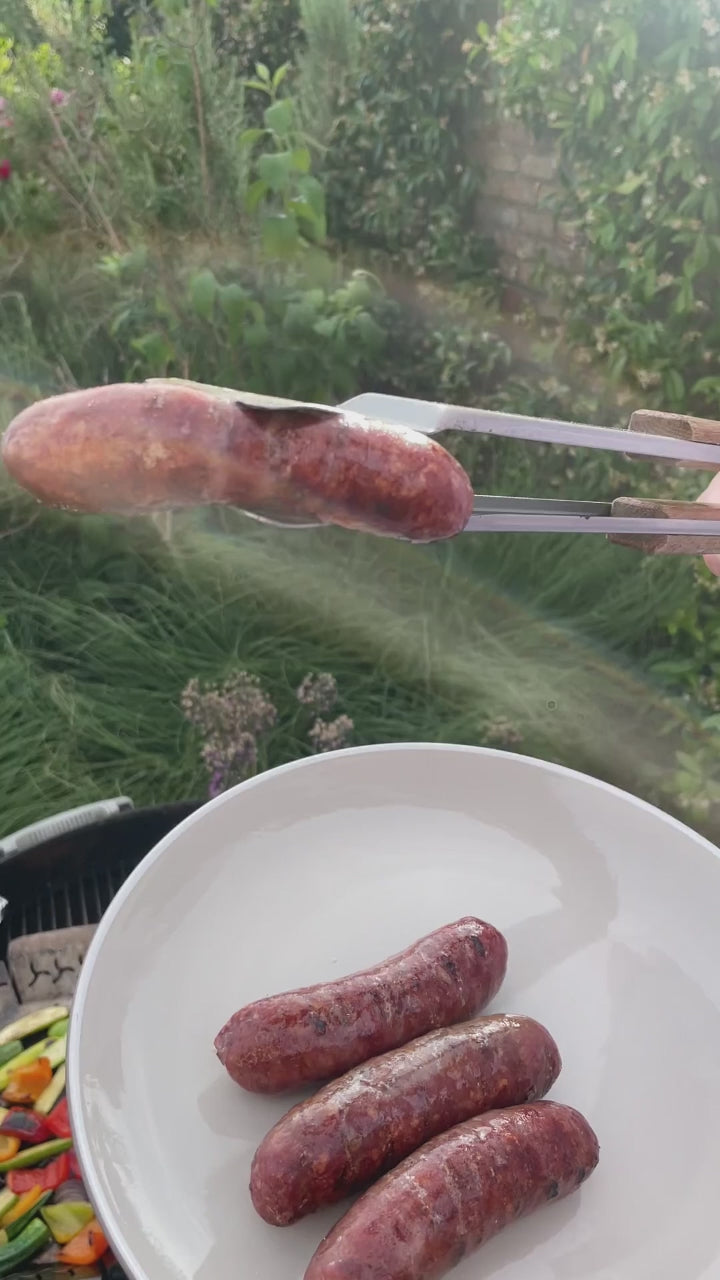 video of venison sausage being picked up from bbq by a pair of tongs