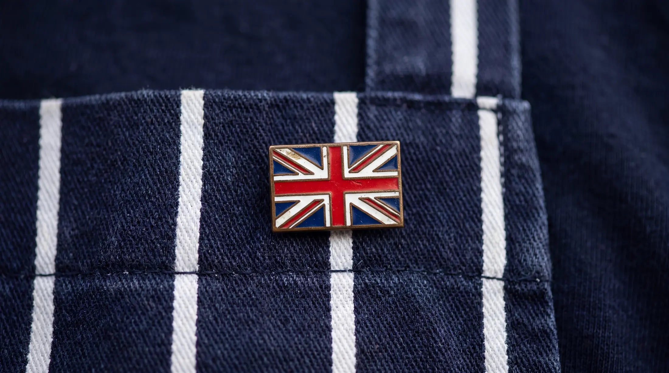 close up shot of stripey navy and white butchers apron with union jack pin